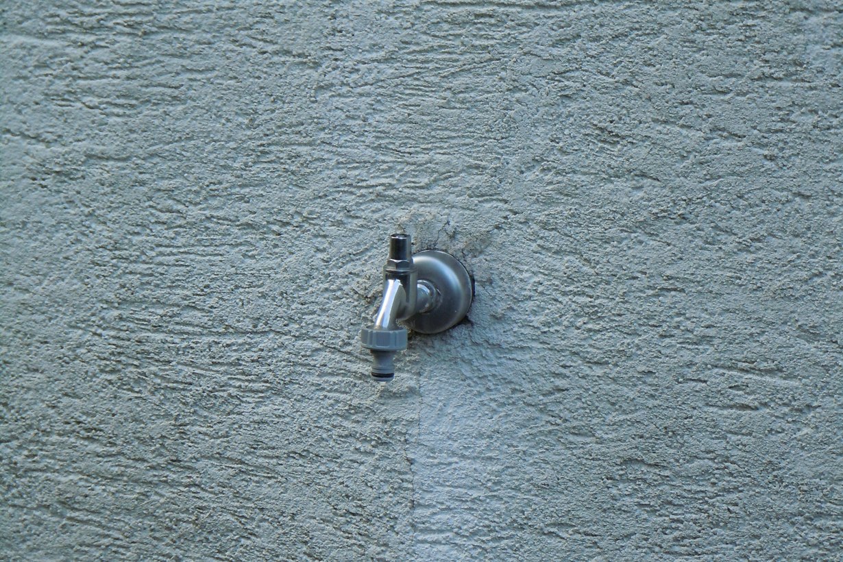 Außenwasserhahn an einer verputzten Hauswand