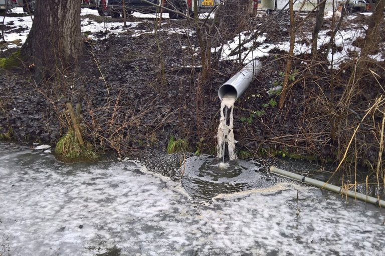 Rohr am Ufer leitet Wasser in einen zugefrorenen Graben