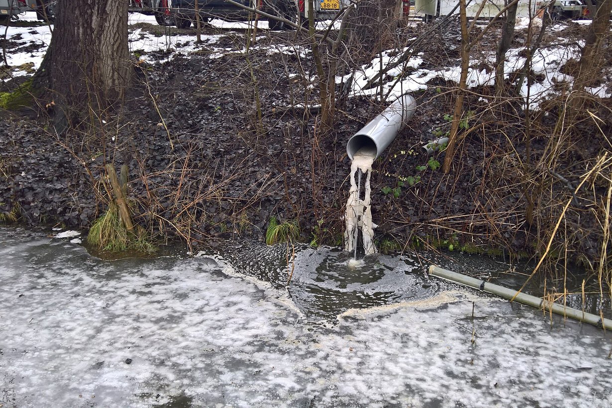 Rohr am Ufer leitet Wasser in einen zugefrorenen Graben
